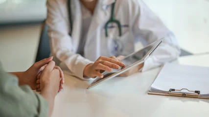 Deurstickers Huisarts Shot van een arts die een patiënt wat informatie laat zien op een digitale tablet