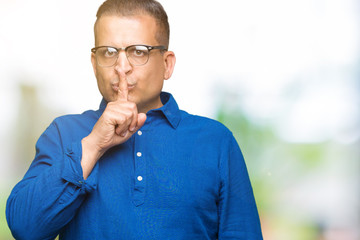 Middle age arab man wearing glasses over isolated background asking to be quiet with finger on lips. Silence and secret concept.