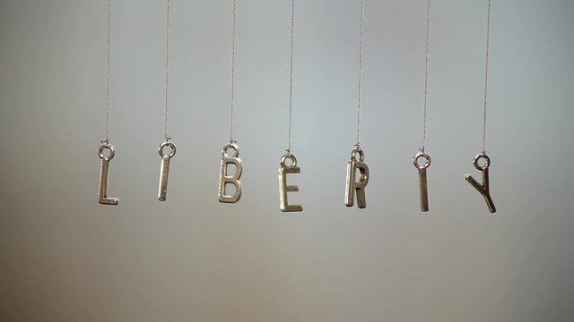 word "liberty" made of metal letters hanging on ropes with blurre...