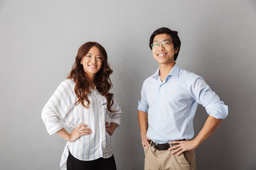 Cheerful asian couple standing over gray background