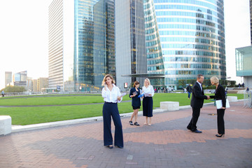 Biz partners advising and calling by smartphone outside.