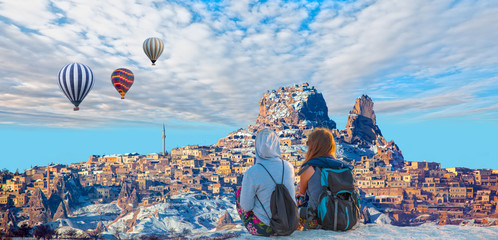 Hot air balloon flying over spectacular Cappadocia - Girls watching the hot air balloon at the hill...