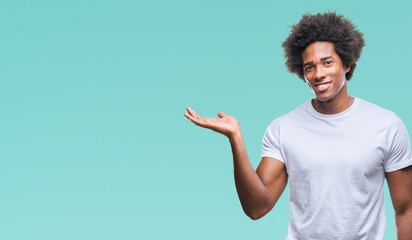 Afro american man over isolated background smiling cheerful presenting and pointing with palm of hand looking at the camera.