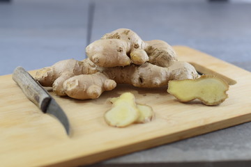 Große, frische Ingwerknolle auf einem Holzbrettchen - Sliced ginger on a wodden plate
