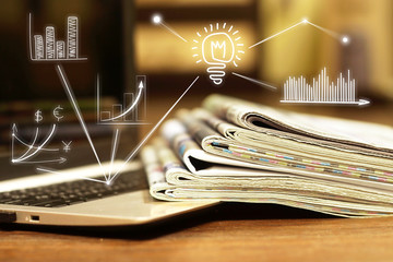 News. Computer and newspapers with virtual graphs and charts as concept for business news. Data analysis and planning