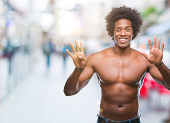 Fototapeta na wymiar Afro american shirtless man showing nude body over isolated background showing and pointing up with fingers number nine while smiling confident and happy.