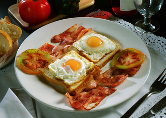 Plato combinado con dos tostadas de pan de molde con dos huevos fritos, beicon y tomate.