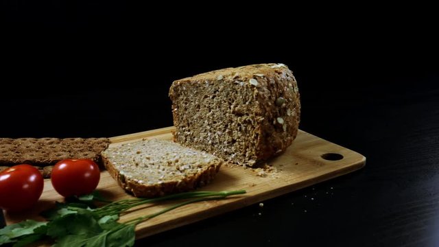 Healthy breakfast. Fresh grain bread,  ripe cherry tomatoes and bread crips with parsley on the cutting board. Camera moves from left to right