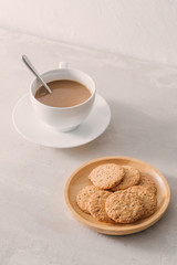 Cup of coffee with milk or cappuccino with cookies on light stone background. Drink with caffeine or cocoa with milk. Coffee break concept.