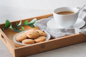 Closeup of coffee with milk in white cup and tasty cookies. Shot on light stone background