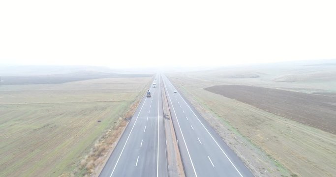 Looking straight down at traffic on a county highway though foggy clouds. 4K Aerial Footage