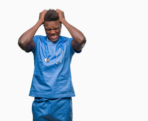 Young african american doctor man over isolated background wearing surgeon uniform suffering from headache desperate and stressed because pain and migraine. Hands on head.