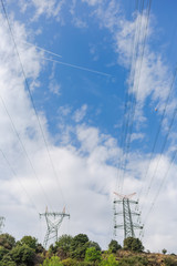 Electricity transmission towers against blue sky background. Vertical color photography.