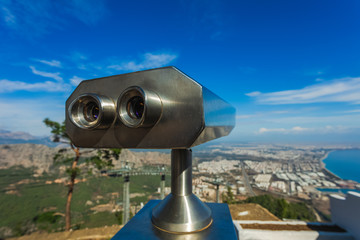 Closeup view of coin operated binocular viewer for looking in details at beautiful summer cityscape landscape. Antalya, Turkey. Happy summer holidays and sightseeing concept. Horizontal photography.