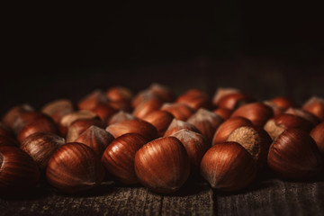close up view of hazelnuts on wooden surface on black background