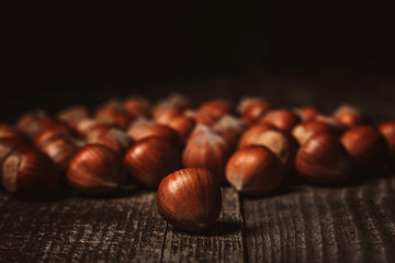 close up view of hazelnuts on wooden surface on black background