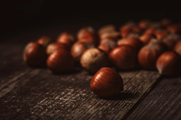 close up view of hazelnuts on wooden surface on black background