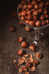 close up view of shelled hazelnuts in glassware on wooden surface