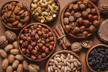 flat lay with variety of nuts in bowls arranged on brown background