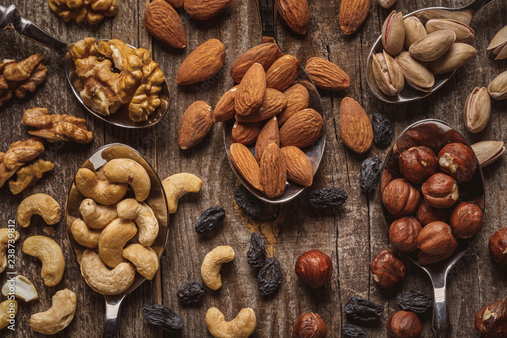 Wall mural flat lay with nuts in spoons on wooden tabletop