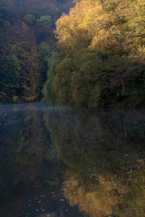river bend with fog over the surface and colorful trees at sunset