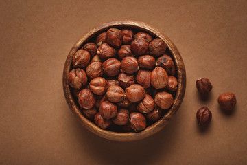 top view of in wooden bowl on shelled chestnuts brown background