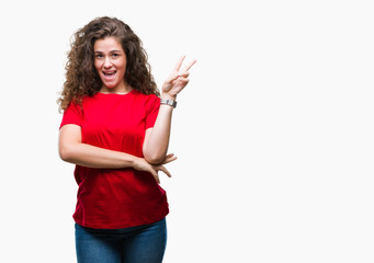 Beautiful brunette curly hair young girl wearing casual look over isolated background smiling with happy face winking at the camera doing victory sign. Number two.