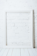 white empty frame on rustic wooden table near brick wall