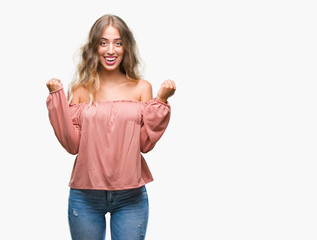 Fototapeta na wymiar Beautiful young blonde woman over isolated background celebrating surprised and amazed for success with arms raised and open eyes. Winner concept.