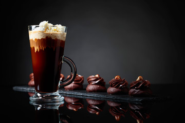  Chocolate dessert with hazelnut and coffee with cream on a black background.
