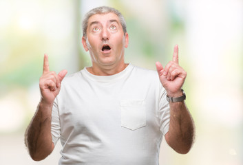 Handsome senior man over isolated background amazed and surprised looking up and pointing with fingers and raised arms.