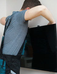 Man mounting new TV on the wall.