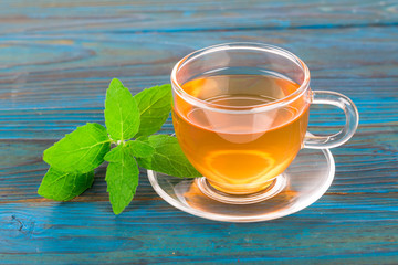 Cup with mint tea on blue table