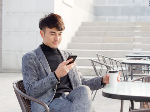 Portrait young business man smiling and using cell phone, typing and reading message or play mobile games, lifestyle concept. 