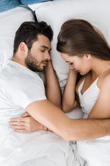 top view of young couple sleeping and embracing in bed