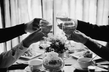 Black and white photo of people holding glasses of wine and clinking