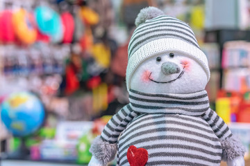 Soft toy smiling snowman in a striped hat and sweater.