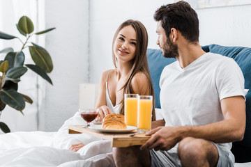 Obraz na płótnie Canvas young couple having breakfast in bedroom