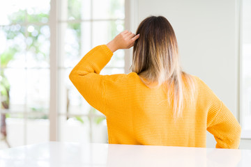 Young beautiful woman wearing winter sweater at home Backwards thinking about doubt with hand on head