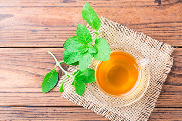 Fresh mint tea with leaves on wooden table