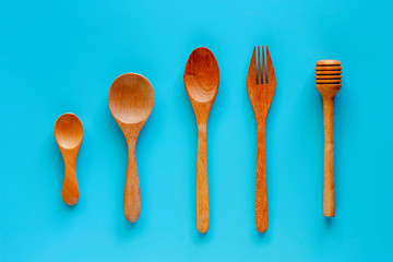 Wooden spoon, fork and honey dipper on blue background for kitchen utensils concept