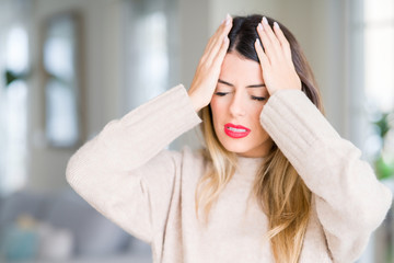 Young beautiful woman wearing winter sweater at home suffering from headache desperate and stressed...