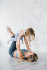 Mother and baby girl do exercises together in the gym