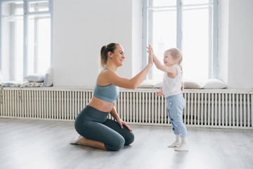 Mother and baby girl do exercises together in the gym