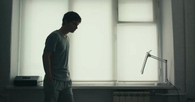 young man is nervous standing by the window