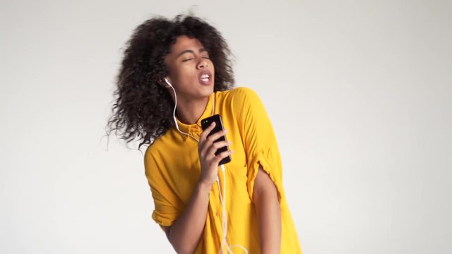 African american woman singing while listening music on mobile phone app