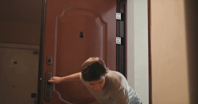young man puts the bag behind the door and quickly closes the door
