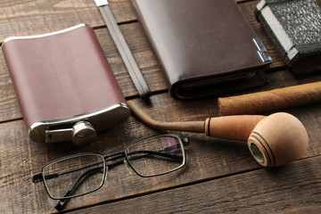 Men's Accessories. men's style. Cigar, perfume, wallet, glasses, flask on a brown wooden background.
