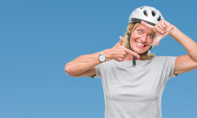 Middle age caucasian cyclist woman wearing safety helmet over isolated background smiling making frame with hands and fingers with happy face. Creativity and photography concept.