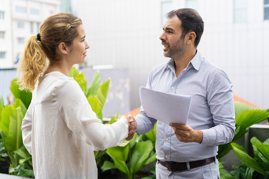 Positive Business Partners Finishing Meeting With Handshake. Business Man And Woman Shaking Hands Outdoors. Dealing Or Partnership Concept